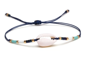 Macro shot of bohemian woven bracelet featuring a natural shell and colorful bead details