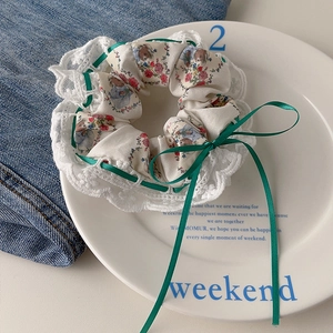 Detail of floral lace scrunchie with green satin bow on a decorative ceramic plate