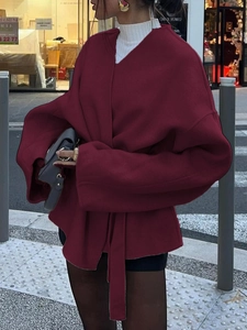 Vue de rue d'un élégant manteau en laine bordeaux pour femme avec une ceinture à nouer chic