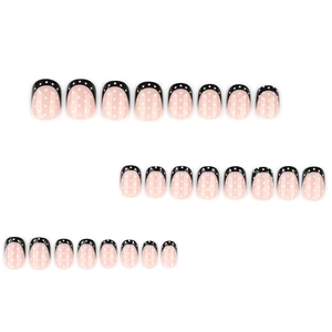 Short square French press-on nails in black and white polka dots on a nude base