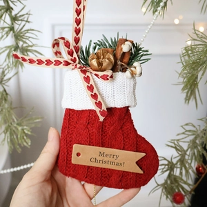 Handcrafted red knit Christmas stocking with pine needles, cinnamon and Merry Christmas tag