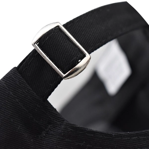 Detail of adjustable cotton baseball cap strap with silver metal buckle on black fabric