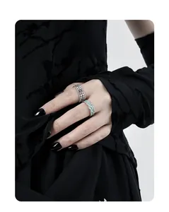 Detailed view of hollow grid silver ring and light green textured band on fingers