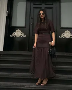 Detailed texture of dark burgundy round neck dress with waist belt and pleated chiffon hem