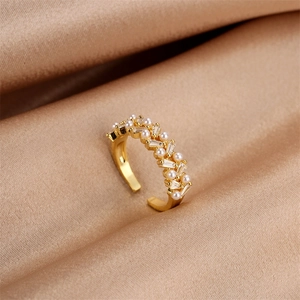Detailed shot of gold pearl ring with rectangular zircon on champagne silk background