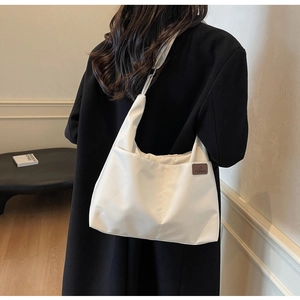 Detailed side view of minimalist white canvas tote bag worn by a model in soft indoor light