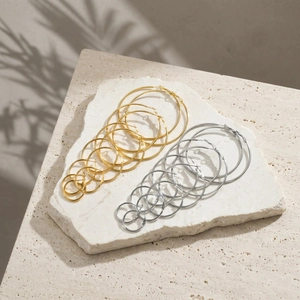 Polished stainless steel hoop earrings in gold and silver set on a stone base