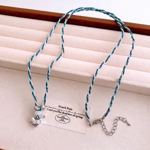 Collier artisanal en cordon de coton bleu et blanc avec pendentif oiseau argenté