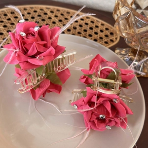 Detail of rose hair claw clip with fabric petals, crystals and soft feather accents