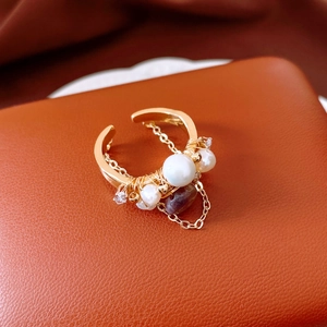 Macro detail of a vintage 18k gold plated ring with pearls and a small chain tassel