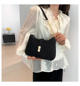Close-up of black shoulder bag with metal chain, leather strap and metallic lock detail