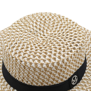 Detailed weave pattern of flat top straw hat with ribbon and silver M badge
