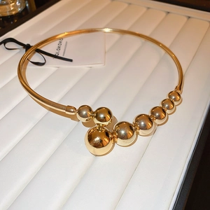 Detailed view of an open gold collar necklace featuring polished gradient metallic spheres