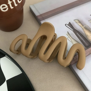 Matte brown wavy hair claw clip in a minimalist design on a beige background