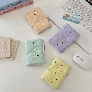 Macro detail of embroidered star fabric passport holders in four pastel colors on a desk