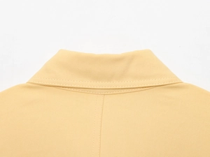 Gros plan de l'encolure jaune pâle montrant la texture du tissu sergé et les coutures