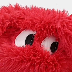 Detailed macro view of the fluffy red plush fabric and cartoon eyes on this winter hat