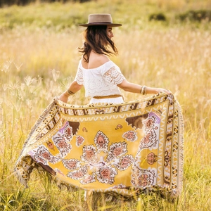 Detail of yellow Bohemian woven picnic blanket with fringe and mandala pattern in outdoor field