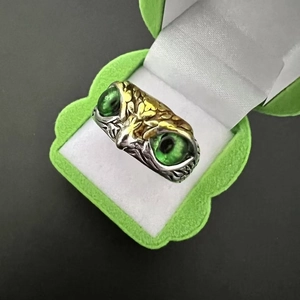 Detailed macro shot of vintage silver owl ring featuring vibrant green gemstone eyes