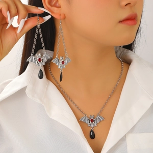 Close-up of silver bat necklace and earrings set with red gems and black pendants