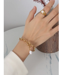 Detail of 18k gold-plated chain bracelet with pearl pendant and matching ring on model