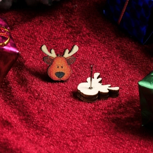 Detailed view of cute wooden reindeer Christmas stud earrings on festive red background