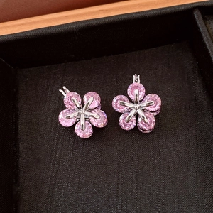 Vue macro détaillée des boucles d'oreilles fleur en zircon rose sur plateau en velours