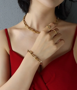 Detailed close-up of 18k gold-plated knotted ring and U-link chain jewelry on model