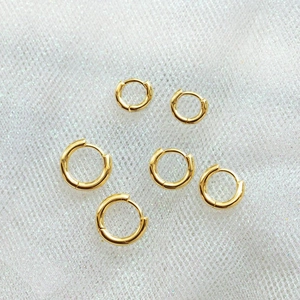 Three sets of polished 18K gold plated hoop earrings in various sizes on white texture