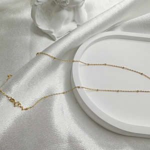 Minimalist S925 sterling silver gold plated bead chain necklace on white silk background