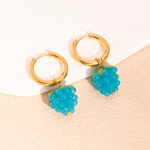 Détail de créoles dorées avec de superbes pendentifs en résine en forme de raisin bleu