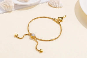 Détail du bracelet doré avec pendentifs cœur et clé et fermoir coulissant ajustable