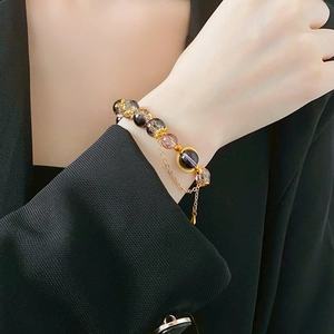 Detail of vintage beaded bracelet with amber glass beads and gold tassel on black blazer