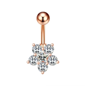 Macro detail of rose gold belly ring featuring a zircon-encrusted flower and star pendant