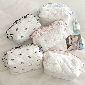Flat lay of quilted cosmetic bags set with bow patterns and ruffled edge detail