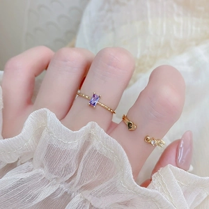 Close-up of gold ring with purple rectangular gemstone and heart detail on lace