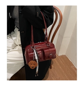 Close-up of wine red glossy bowling bag with plush dog charm and buckle pockets