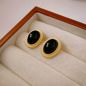 Close-up of vintage oval gold earrings with black gemstone in a jewelry box