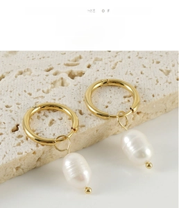 Detailed close-up of gold stainless steel hoop earrings with hanging baroque pearls