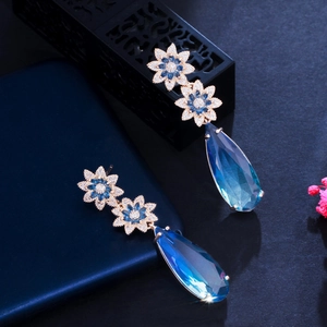 Detail of long gold drop earrings with blue waterdrop sapphire and floral zircon stones