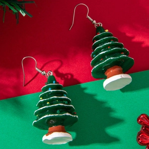 Close-up of green Christmas tree drop earrings with colorful ornaments on festive background