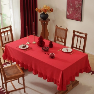 Close-up of red tablecloth with ruffled edges on a dining table in a cozy room