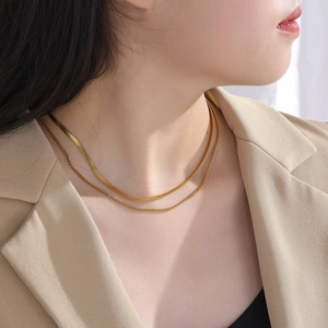 Golden double-layer snake bone necklace and fine chain set on a model neckline