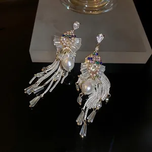 Elegant gold drop earrings with colorful crystals, pearls and long tassels on black display