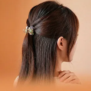 Golden flower hair claw with green beads and pearls on hair for elegant styling