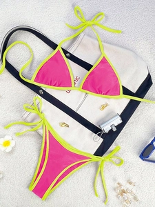 Flat lay of pink and yellow bikini set with summer beach accessories and sunglasses