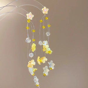 Detailed view of handmade floral tassel earrings with yellow beads and star accents