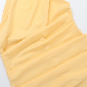 Close-up detail of light yellow pleated fabric on this summer backless halter dress