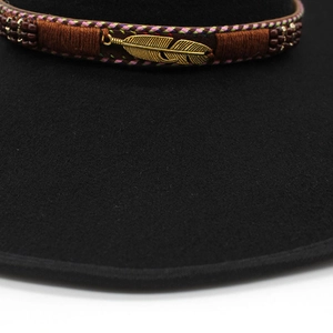 Macro shot of brown embroidered hat band with beads and golden feather detail