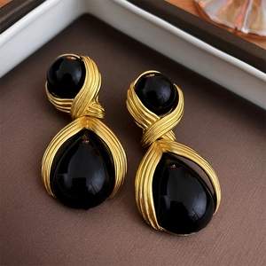 Detailed view of dark teardrop earrings with vintage gold metal wrap and resin stones